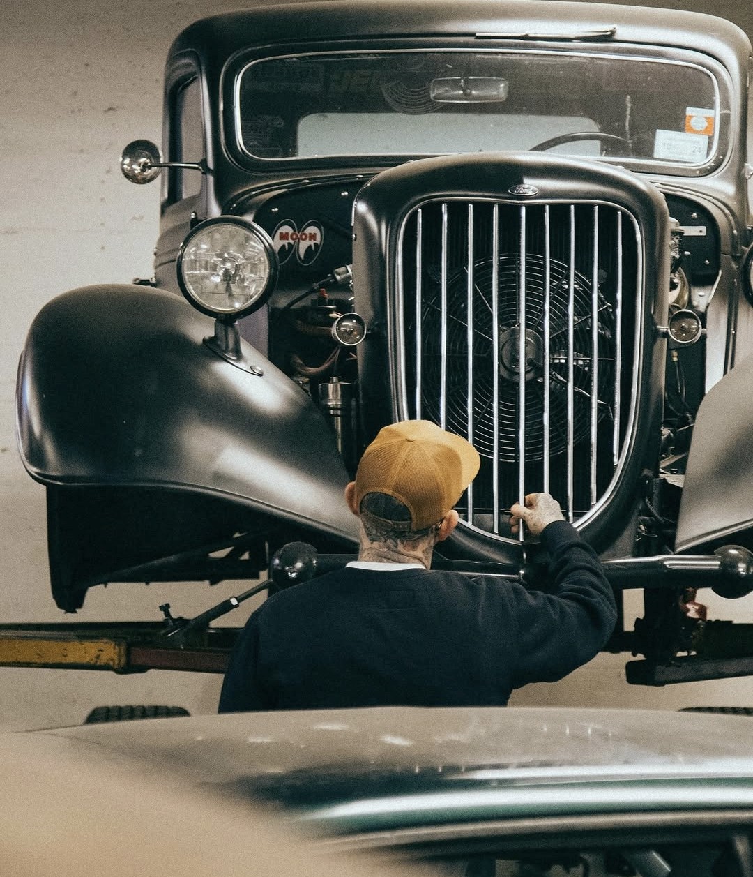 Builder working on a hot rod grille in a garage